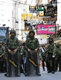 Thai soldiers wait along the street of Patpong red light district off Silom road in the financial district of Bangkok on April 20, 2010.  Hundreds of Thai troops, many of them armed, were deployed on the streets of Bangkok to protect the city's financial heart from anti-government rallies. Military and riot police were deployed in the central financial district, known as Silom, close to the Reds' current rally base in the capital's commercial heartland.   AFP PHOTO / ROSLAN RAHMAN (Photo credit should read ROSLAN RAHMAN/AFP/Getty Images)